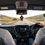 Two men driving through a scenic landscape, using a cellphone for navigation.
